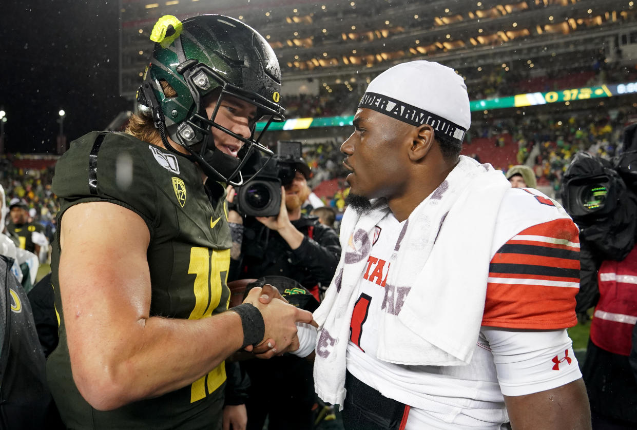 Justin Herbert #10 of the Oregon Ducks shakes hands with quarterback Tyler Huntley #1 of the Utah Utes after the Ducks defeated the Utes 37-15 in the Pac-12 title game. (Thearon W. Henderson/Getty Images)