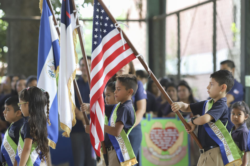 Niños salvadoreños portan las banderas nacionales de Estados Unidos y El Salvador en una ceremonia de bienvenida a un grupo de donantes estadounidenses, en la escuela Hosanna, una institución manejada por la Iglesia Asambleas de Dios, en una zona antes controlada por las pandillas, en Santa Ana, El Salvador, el sábado 29 de abril de 2023. (AP Foto/Salvador Meléndez)