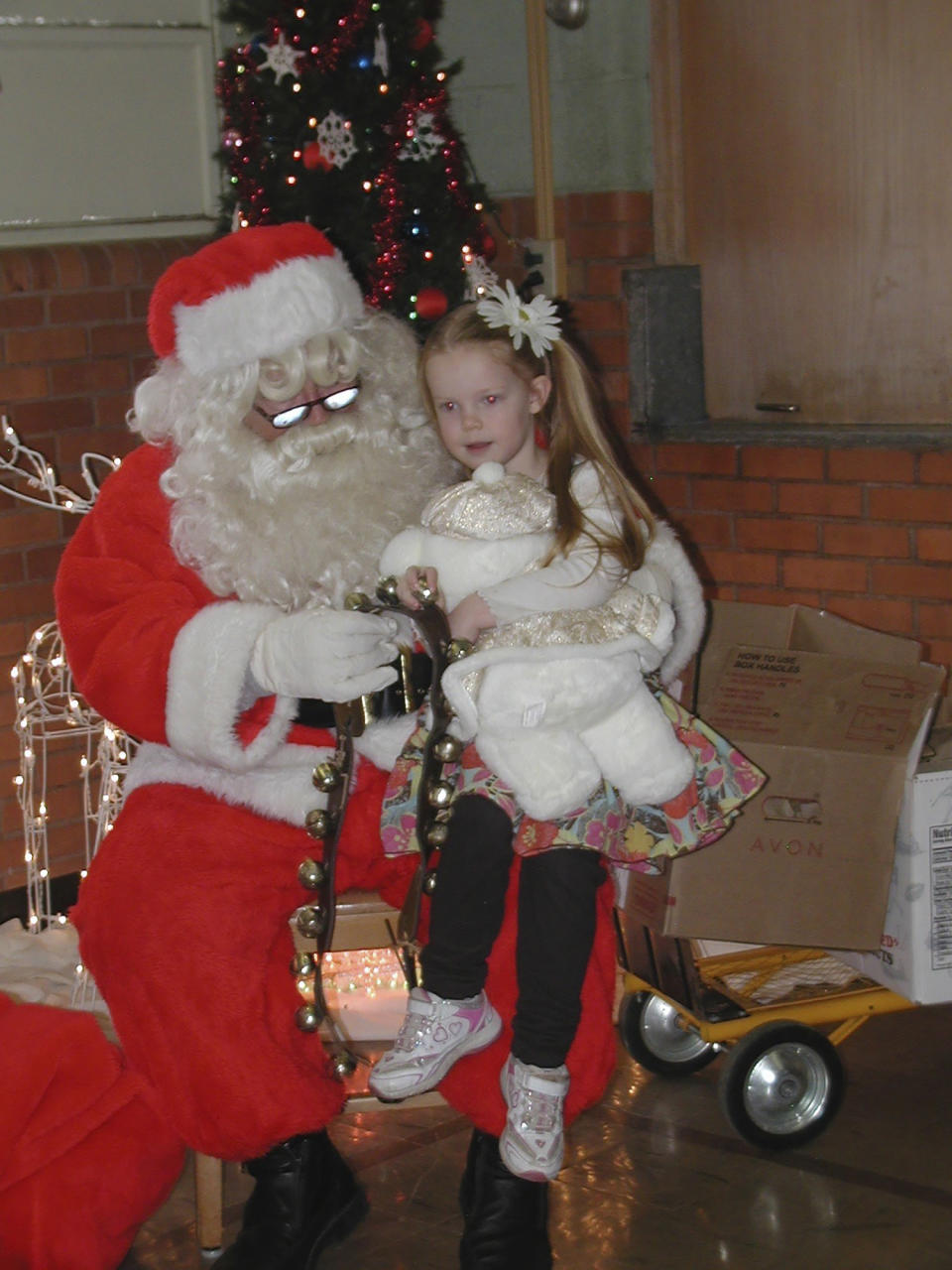 This Dec. 15, 2012, photo provided by Carolyn Plotts, Evelyn Spanier, 4, visits with Santa following the annual Norcatur Christmas Drawing in Norcatur, Kan. For the 150 or so people who still call this rural hamlet home, the cancellation in 2020 of the town's beloved Norcatur Christmas Drawing has shone a spotlight on a global coronavirus pandemic that has reached deep into rural America. (Courtesy of Carolyn Plotts via AP)