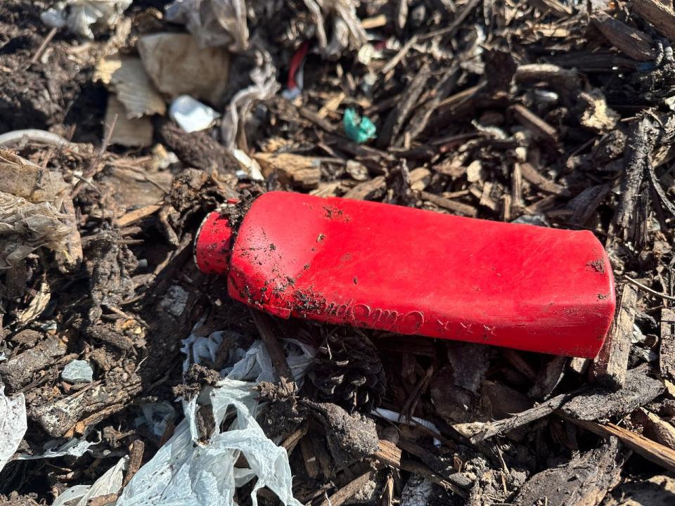 A plastic hygiene product bottle among the organics piled at Yellowknife's compost facility. Vaughn said items like this are sifted out at the end of the composting process.