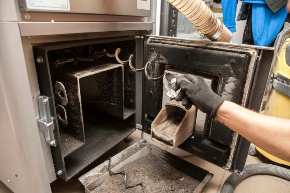A close up of a worker's hand tending to a pellet stove. 