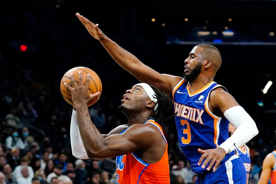 Oklahoma City Thunder forward Luguentz Dort, left, tries to get off a shot as Phoenix Suns guard Chris Paul (3) defends during the first half of an NBA basketball game Wednesday, Dec. 29, 2021, in Phoenix. (AP Photo/Ross D. Franklin)