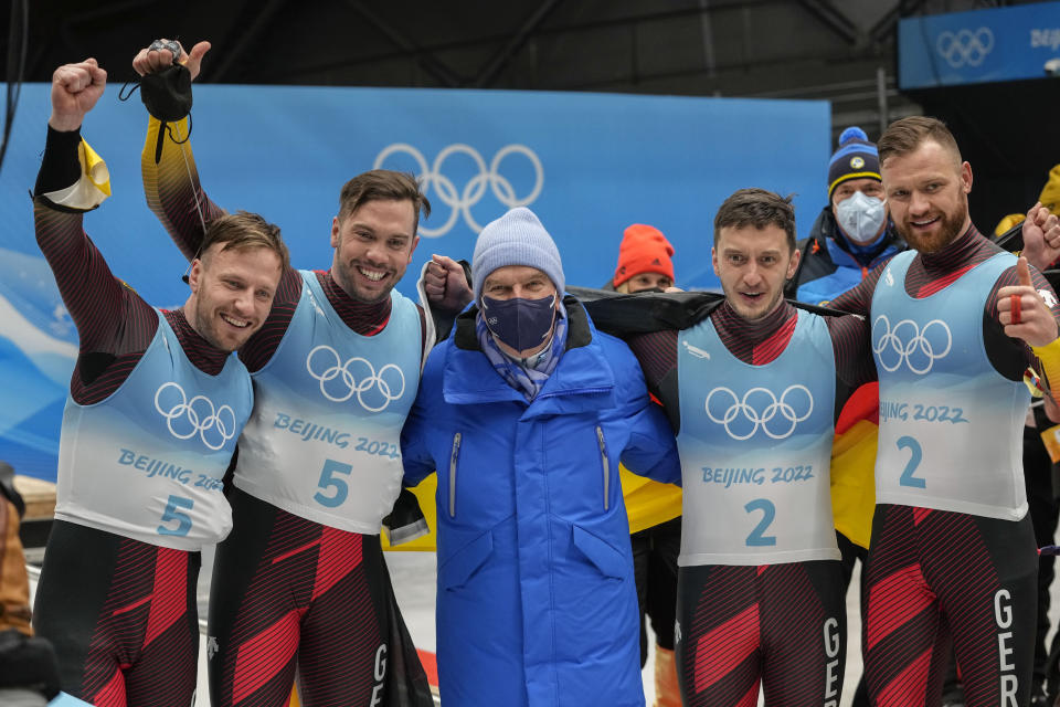 Tobias Wendl and Tobias Arlt, of Germany, left, and teammates Toni Eggert and Sascha Benecken celebrate with IOC president Thomas Bach after winning the gold and silver medals in the luge doubles at the 2022 Winter Olympics, Wednesday, Feb. 9, 2022, in the Yanqing district of Beijing. (AP Photo/Mark Schiefelbein)