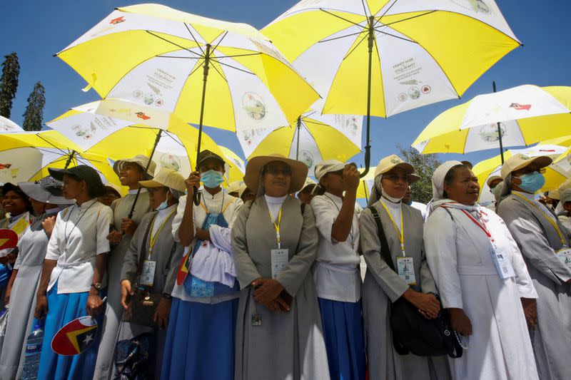 People hold umbrellas as they gather to welcome Pope Francis ahead of his arrival in Dili