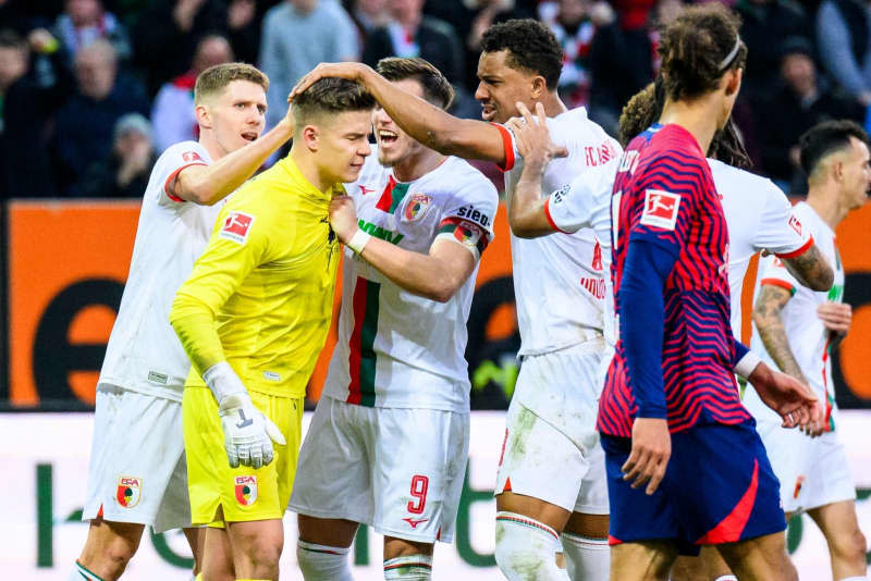 Augsburg goalkeeper Finn Dahmen (2nd L) celebrates with Augsburg's Kristijan Jakic (L), Augsburg's Ermedin Demirovic (2nd R) and Augsburg's Felix Uduokhai (R) after his penalty save during the German Bundesliga soccer match between FC Augsburg and RB Leipzig at WWK-Arena. Tom Weller/dpa