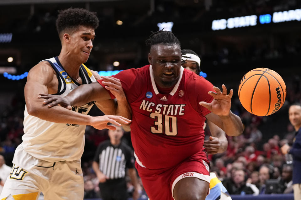 North Carolina State's DJ Burns Jr. (30) and Marquette's Oso Ighodaro, left, compete for the ball during the first half of a Sweet 16 college basketball game in the NCAA Tournament in Dallas, Friday, March 29, 2024. (AP Photo/Tony Gutierrez)