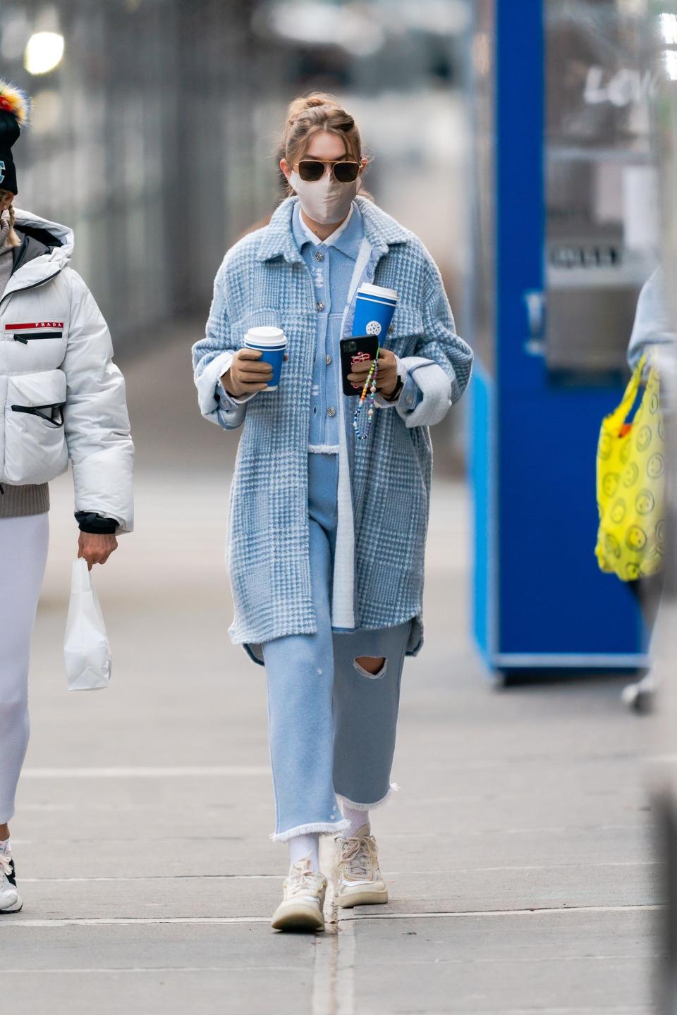 Gigi seen in jeans and a jacket, carrying coffee cups