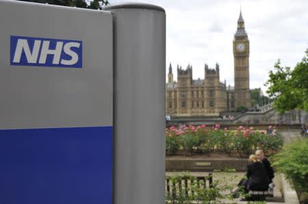 A National Health Service (NHS) sign is seen in the grounds of St Thomas' Hospital, in front of the Houses of Parliament in London June 7, 2011. REUTERS/Toby Melville