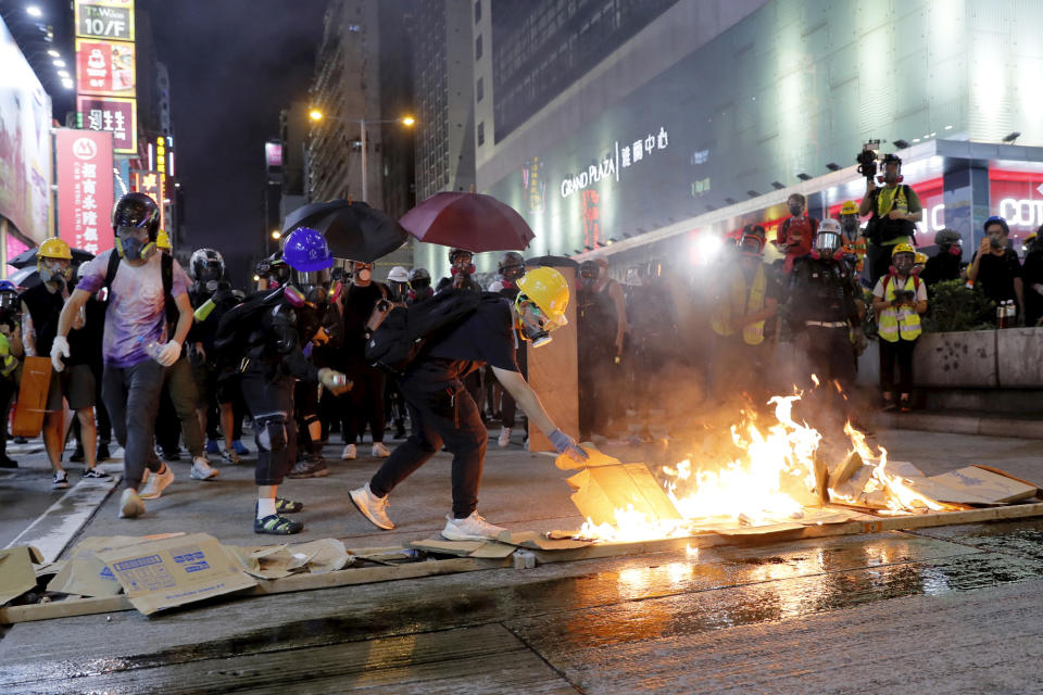 Protesters burn cardboard to form a barrier as they confront with police in Hong Kong on Saturday, Aug. 3, 2019. Hong Kong protesters removed a Chinese national flag from its pole and flung it into the city's iconic Victoria Harbour on Saturday, and police later fired tear gas at demonstrators after some of them vandalized a police station. (AP Photo/Kin Cheung)