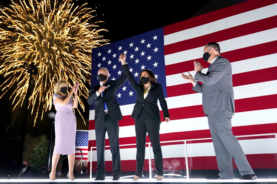 El candidato demócrata a la presidencia de Estados Unidos, el exvicepresidente Joe Biden, y si compañera de fórmula, la senadora de California Kamala Harris, levantan el brazo mientras estallan fuegos artificiales durante la cuarta y última jornada de la Convención Nacional Demócrata, el 20 de agosto de 2020, en el Chase Center de Wilmington, Delaware. Junto a ellos en el escenario están Jill Biden (en el extremo izquierdo) y el esposo de Harris, Doug Emhoff (en el extremo derecho). (AP Foto/Andrew Harnik)