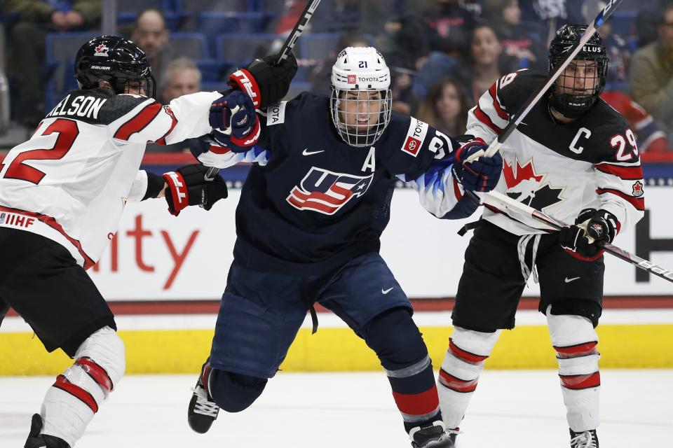 FILE - In this Dec. 14, 2019, file photo, Canada's Meaghan Mikkelson (12) and Marie-Philip Poulin (29) defends against United States' Hilary Knight (21) during the third period of a rivalry series women's hockey game in Hartford, Conn. Knight has played in rinks large and small spanning globe during her 14 years representing USA Hockey. That does not prevent the three-time Olympian from getting chills in anticipation of hitting the ice for the first time at Madison Square Garden on Sunday, Feb. 28, 2021, for the opening stop of the Professional Women’s Hockey Players’ Association Dream Gap Tour's second season. (AP Photo/Michael Dwyer, File)