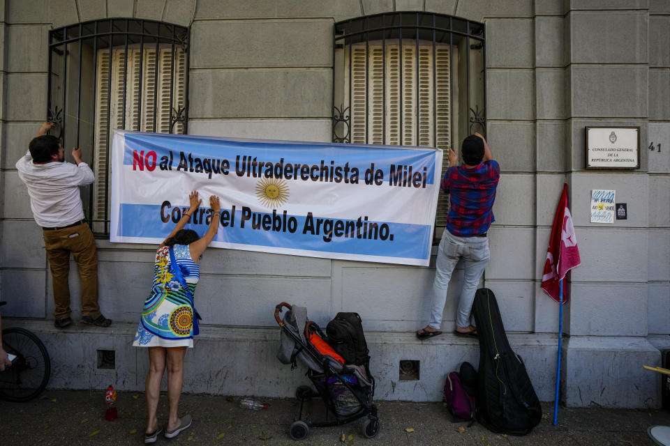 Activists in support of the national strike in Argentina against economic and labor reforms proposed by President Javier Milei, hang on the facade of the Argentine consulate, a banner with a message that reads in Spanish: "No to Milei's far-right attack on the Argentine people", in Santiago, Chile, Wednesday, Jan. 24, 2024. (AP Photo/Esteban Felix)