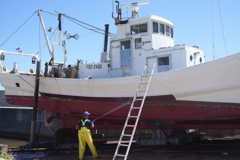 A worker cleans a fishing boat at Numanouchi port, Iwaki, northeastern Japan, near the Fukushima Daiichi nuclear power plant, damaged by a massive March 11, 2011, earthquake and tsunami, on Friday, Aug. 25, 2023. Fish auction prices at a port south of the Fukushima Daiichi nuclear power plant Friday somehow dipped amid uncertainty about how consumers may respond a day after release to sea of treated and diluted radioactive wastewater began despite protests at home and in neighboring countries. (AP Photo/Eugene Hoshiko)