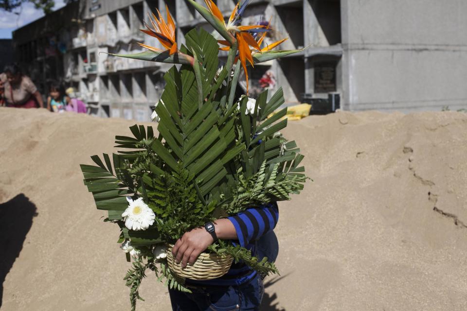 A woman holds a flowers bouquet during the burial of 14-year-old Madelyn Patricia Hernandez Hernandez, a girl who died in a fire at the Virgin of the Assumption Safe Home, at the Guatemala City's cemetary, Friday, March 10, 2017. Families began burying some of the 36 girls killed in a fire at an overcrowded government-run youth shelter in Guatemala as authorities worked to determine exactly what happened. (AP Photo/Moises Castillo)