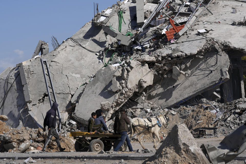 Palestinians ride on a donkey cart past factories destroyed in the Israeli bombardment of the Gaza Strip in Deir al Balah, Gaza Strip, Thursday, Feb. 15, 2024. (AP Photo/Adel Hana)