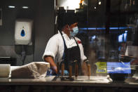 A chef wears a protective mask in a kitchen of a restaurant in Soho, in London, Tuesday, Sept. 22, 2020. Britain's Prime Minister, Boris Johnson, has announced that pubs and restaurants closing at 10pm, due to the spike of cases of coronavirus across the United Kingdom. (AP Photo/Alberto Pezzali)