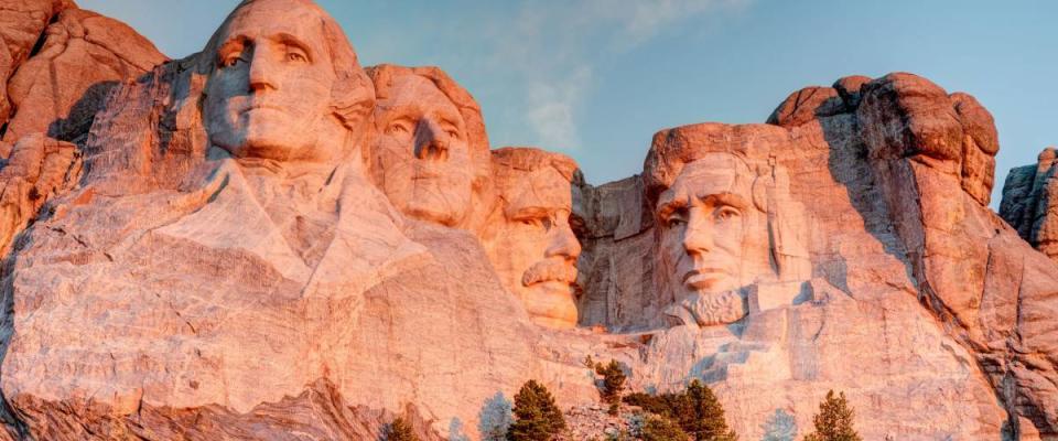 Mount Rushmore National Park in the Black Hills South Dakota during a warm sunrise with clear blue sky morning. High Dynamic Range. / Mount Rushmore National Park