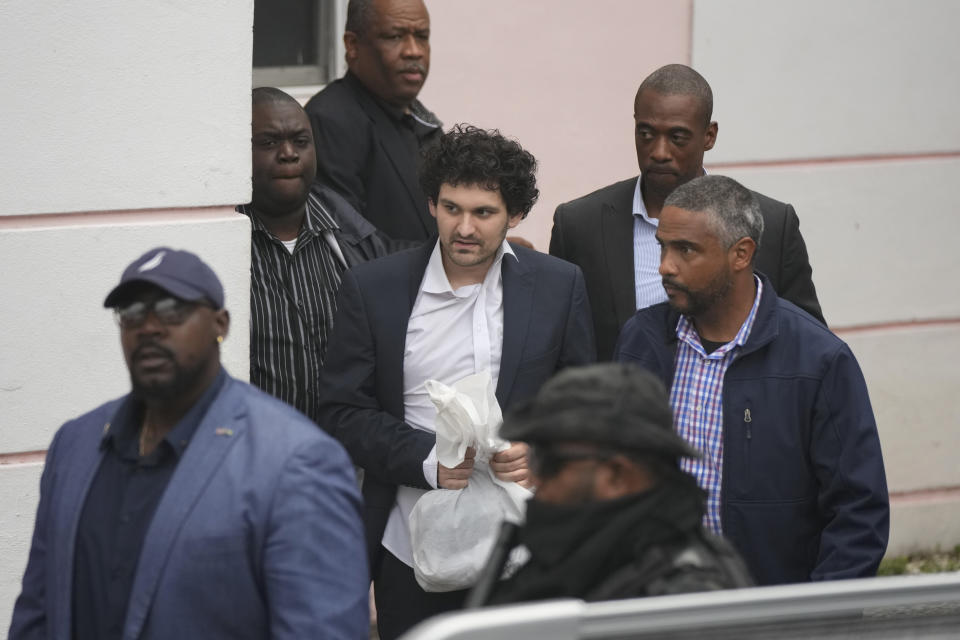 FTX founder Sam Bankman-Fried, center, is escorted from the Magistrate Court in Nassau, Bahamas, Wednesday, Dec. 21, 2022, after agreeing to be extradited to the U.S. (AP Photo/Rebecca Blackwell)