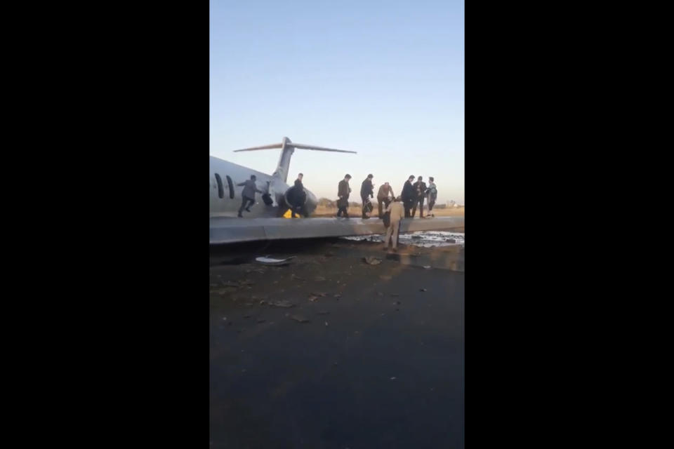 In this image from video shot by Iran's Civil Aviation Network News, passengers walk off over the wing of a crashed plane in Mahshahr, Iran, Monday, Jan. 27, 2020. The Iranian passenger airliner carrying some 150 passengers skidded off the runway and into a street next to the airport in the southern city of Mahshahr on Monday, after apparently losing its landing gear in a hard landing. (Iran's Civil Aviation Network News via AP)