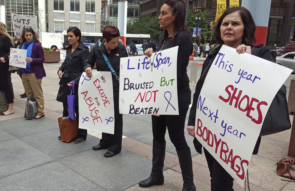 FILE - In this Oct. 1, 2015 file photo, advocates for victims of domestic abuse protest outside of state offices in downtown Chicago. The Illinois Department of Human Services waited five months to inform dozens of domestic violence shelters there was no money for them in a temporary budget lawmakers approved last summer. Officials providing services to victims of domestic violence tell The Associated Press they were unaware that about $9 million in state funding was left out of the stopgap plan that expired in December. (AP Photo/Sophia Tareen, File)