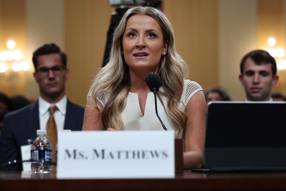 Sarah Matthews behind nameplate and microphone in commitee room