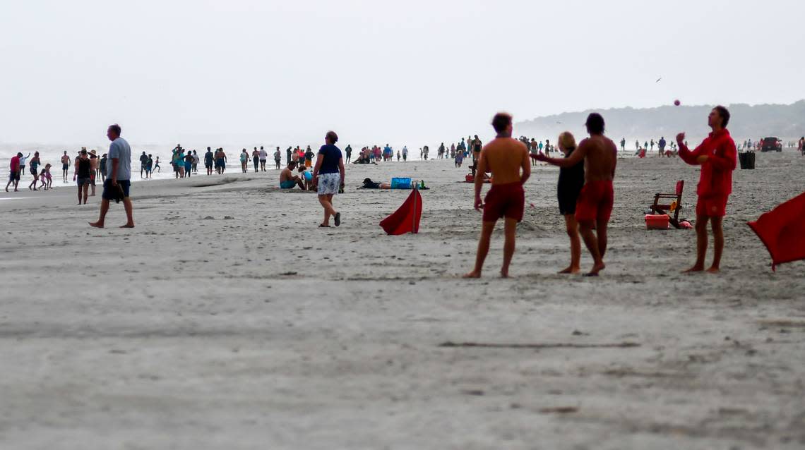 Lifeguards with Shore Beach Services, foreground, gather together near Coligny Beach Park on Monday, August 3, 2020, on Hilton Head Island as a number of beach goers came to the beach to see the rough surf whipped up by tropical storm Isaias. Lifeguards were flying red flags warning swimmers of rough surf caused as the storm moved along the eastern seaboard.