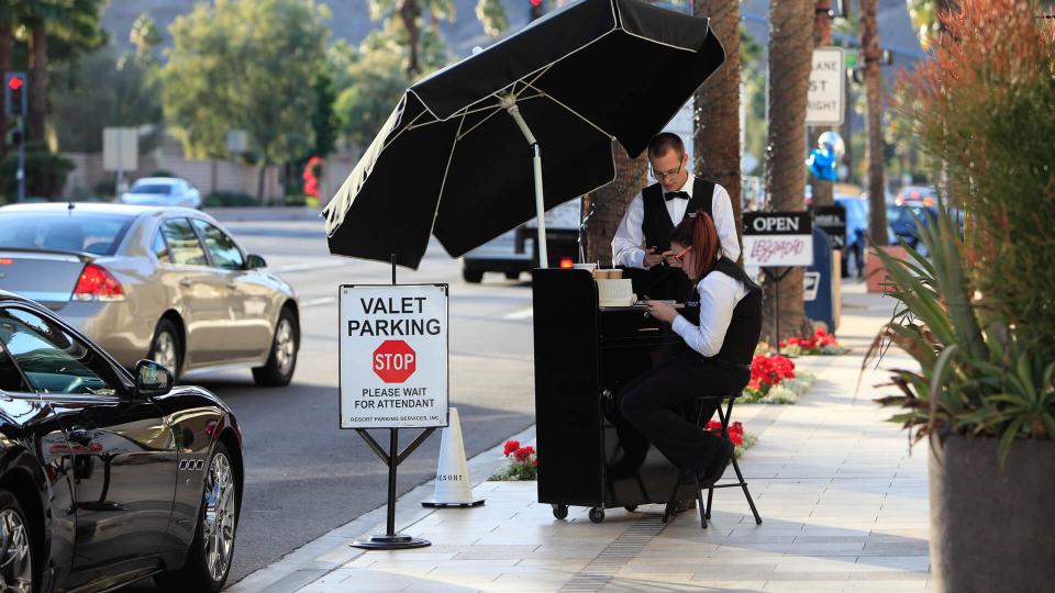 Palm Desert, United States - December 3, 2012: Two valet parking attendants in uniforms at a cubside kiosk in El Paseo Palm Desert.