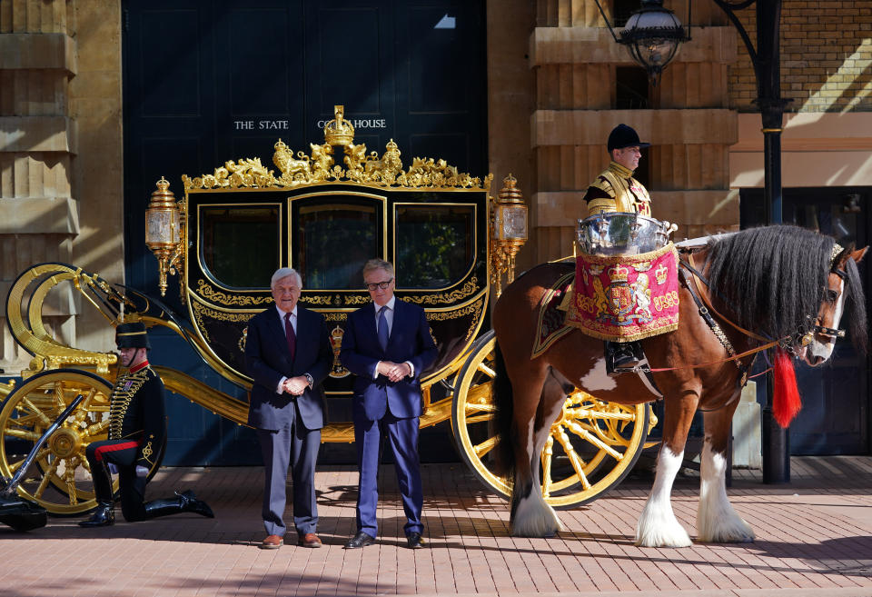 <p>Simon Brooks-Ward, Producer and Director, (right) and Sir Mike Rake, Chairman of the Advisory Committee, pose for a photograph in front of the Diamond Jubilee State Coach, during the media launch for the Queen's Platinum Jubilee celebration at the Royal Mews, Buckingham Palace, London. In 2022 Queen Elizabeth II will become the first British Monarch to celebrate a Platinum Jubilee - seventy years of service - having acceded to the throne on 6th February 1952. Picture date: Tuesday September 21, 2021.</p>
