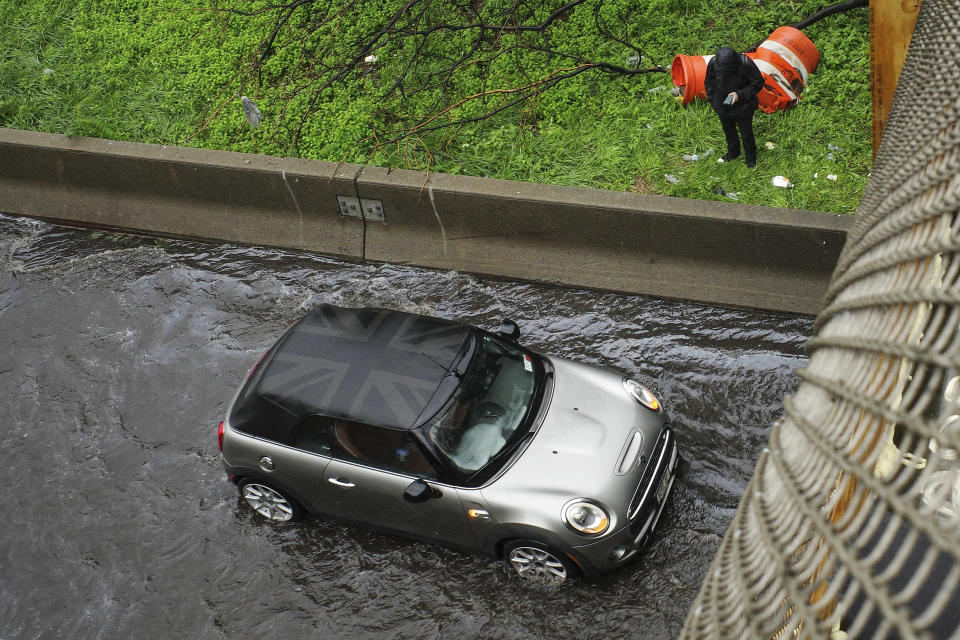 A man stands in the median next to his car stranded in flood waters on the Brooklyn Queens Expressway, Friday, Sept. 29, 2023, in New York. A potent rush-hour rainstorm has swamped the New York metropolitan area. The deluge Friday shut down swaths of the subway system, flooded some streets and highways, and cut off access to at least one terminal at LaGuardia Airport. (AP Photo/Robert Bumsted)