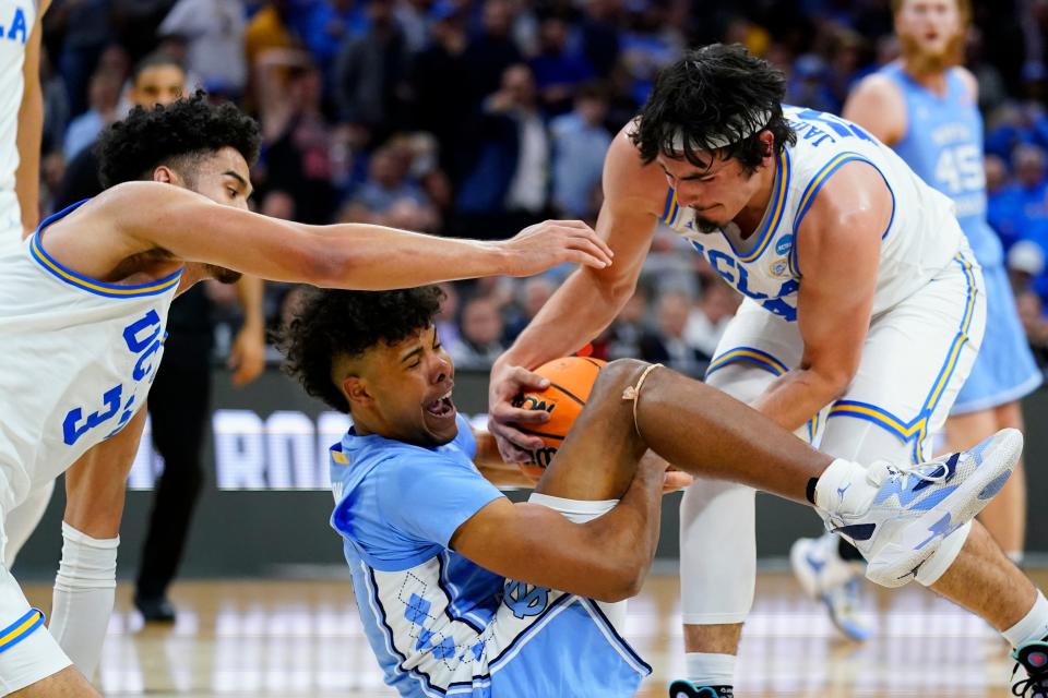 North Carolina's Puff Johnson, center, battles for a loose ball with UCLA's Johnny Juzang, left, and Jaime Jaquez Jr. during the second half of a college basketball game in the Sweet 16 round of the NCAA tournament, Friday, March 25, 2022, in Philadelphia.