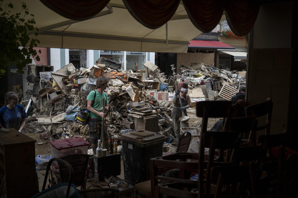 Paddy Amanatidis, right, cleans up in front of her restaurant that was flooded in Bad Neuenahr-Ahrweiler, Germany, Monday July 19, 2021. More than 180 people died when heavy rainfall turned tiny streams into raging torrents across parts of western Germany and Belgium, and officials put the death toll in Ahrweiler county alone at 110. (AP Photo/Bram Janssen)