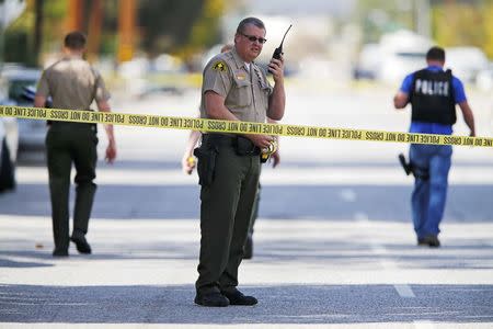 FBI and police investigators examine evidence at the scene of the investigation around the area of the SUV vehicle where two suspects were shot by police following a mass shooting in San Bernardino, California December 3, 2015. REUTERS/Mike Blake