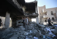 People inspect the wreckage of buildings that were damaged by Saudi-led coalition airstrikes, in Sanaa, Yemen, Tuesday, Jan. 18, 2022. The coalition fighting in Yemen announced it had started a bombing campaign targeting Houthi sites a day after a fatal attack on an oil facility in the capital of the United Arab Emirates claimed by Yemen’s Houthi rebels. It said it also struck a drone operating base in Nabi Shuaib Mountain near Sanaa. (AP Photo/Hani Mohammed)