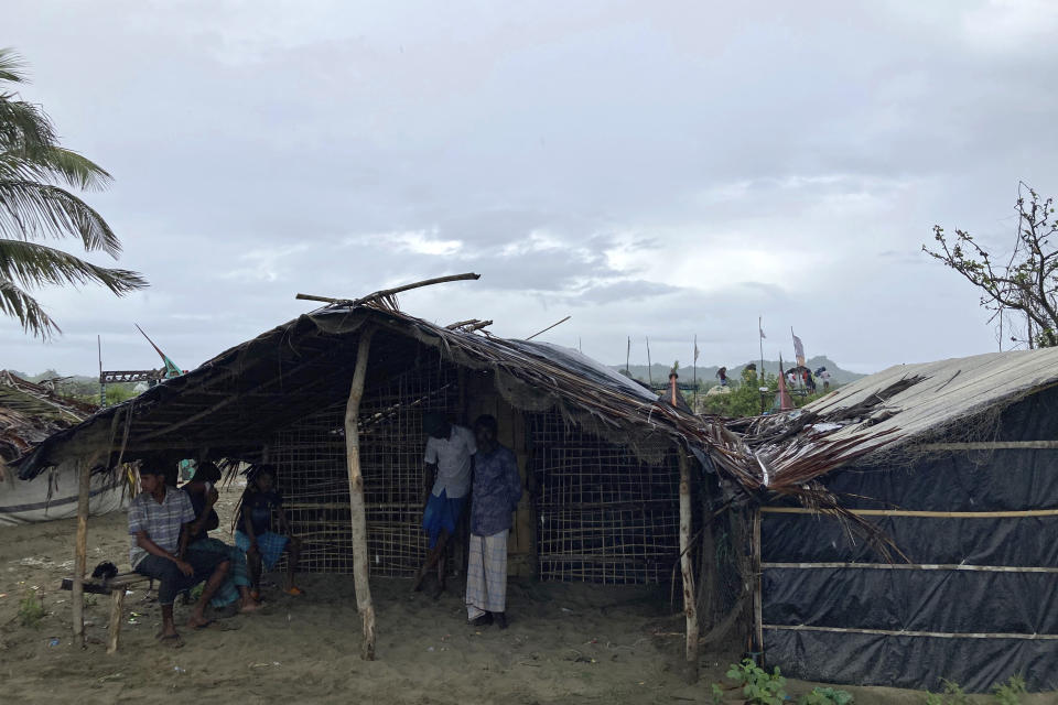 Fisherman take shelter under a shack near the coast in Cox's Bazar district, Bangladesh, Sunday, May 14, 2023. Bangladesh and Myanmar are bracing as an extremely severe cyclone starts to hit their coastal areas, and authorities urged thousands of people in both countries to seek shelter. (AP Photo/Al-emrun Garjon)