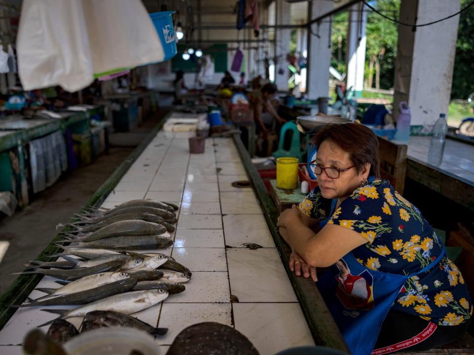 A fish vendors leans on a table lined with fish waiting for customers at a wet market on March 8 in Pola, Oriental Mindoro.