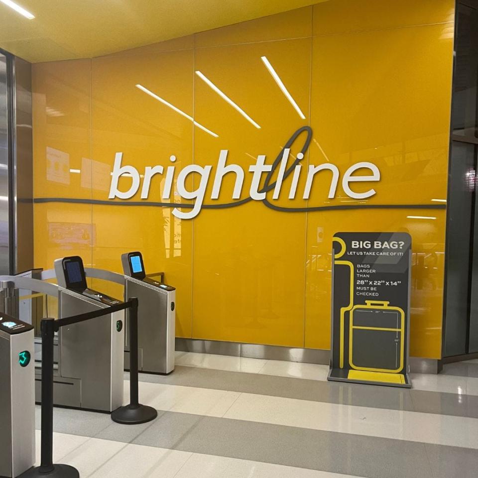 yellow wall with brightline sign next to ticket-scanning stations