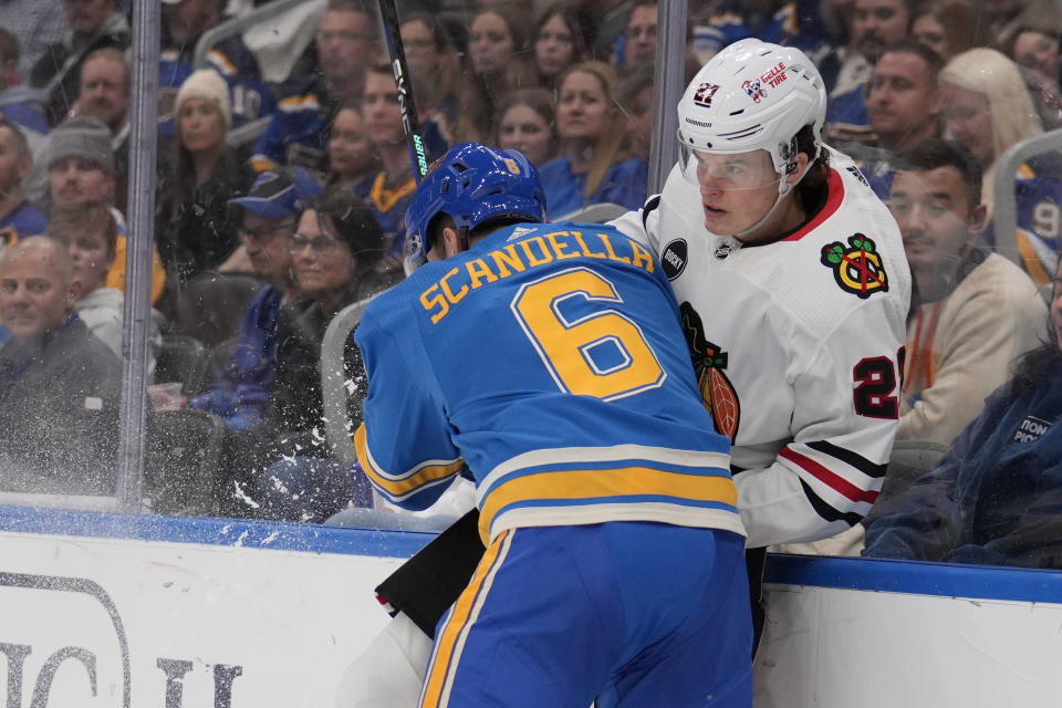 Chicago Blackhawks' Lukas Reichel is checked by St. Louis Blues' Marco Scandella (6) during the first period of an NHL hockey game Saturday, Dec. 23, 2023, in St. Louis. (AP Photo/Jeff Roberson)