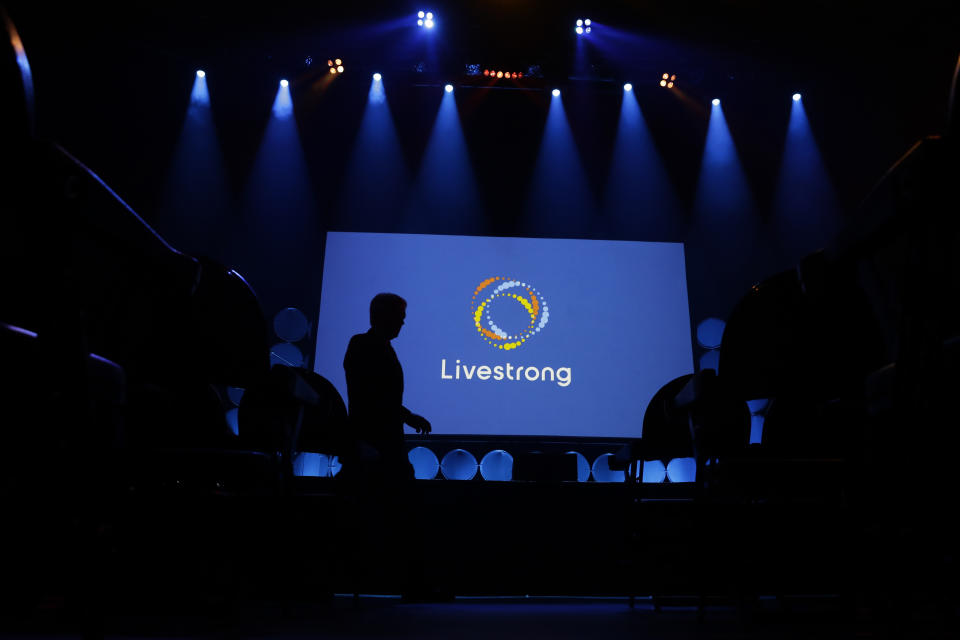 In this Monday, Feb. 3, 2020 photo, a guest walks past the new logo for Livestrong at an event in Austin, Texas. The Livestrong cancer charity is on a mission to reinvent itself. It has survived a dramatic fall in contributions and donations since founder Lance Armstrong's performance-enhancing drug scandal. (AP Photo/Eric Gay)