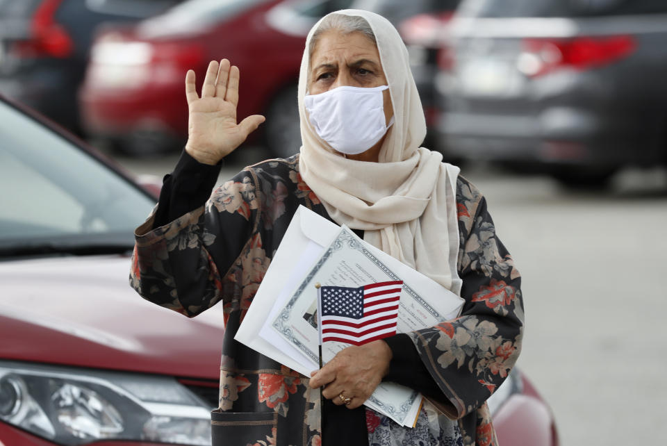 FILE - In this June 26, 2020, file photo, Aisha Kazman Kammawie, of Ankeny, Iowa, takes the oath of allegiance during a drive-thru naturalization ceremony at Principal Park in Des Moines, Iowa. U.S. Citizenship and Immigration Services has transformed under President Donald Trump to emphasize fraud detection, enforcement and vetting, which has delayed processing and contributed to severe fiscal problems. Its revamp came as the administration sought to cut legal immigration by making it more dependent on employment skills and wealth tests. (AP Photo/Charlie Neibergall, File)