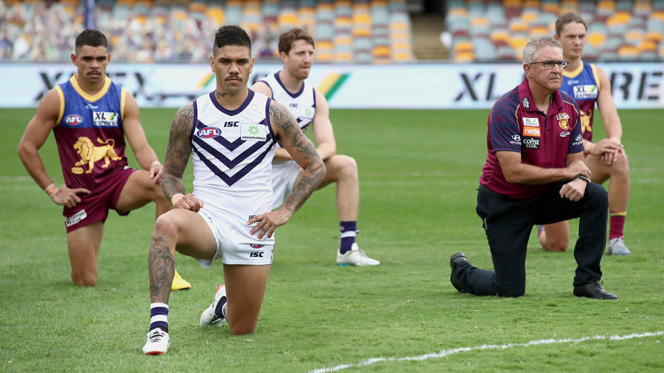 Fremantle and Brisbane players, pictured here taking a knee before their AFL game.