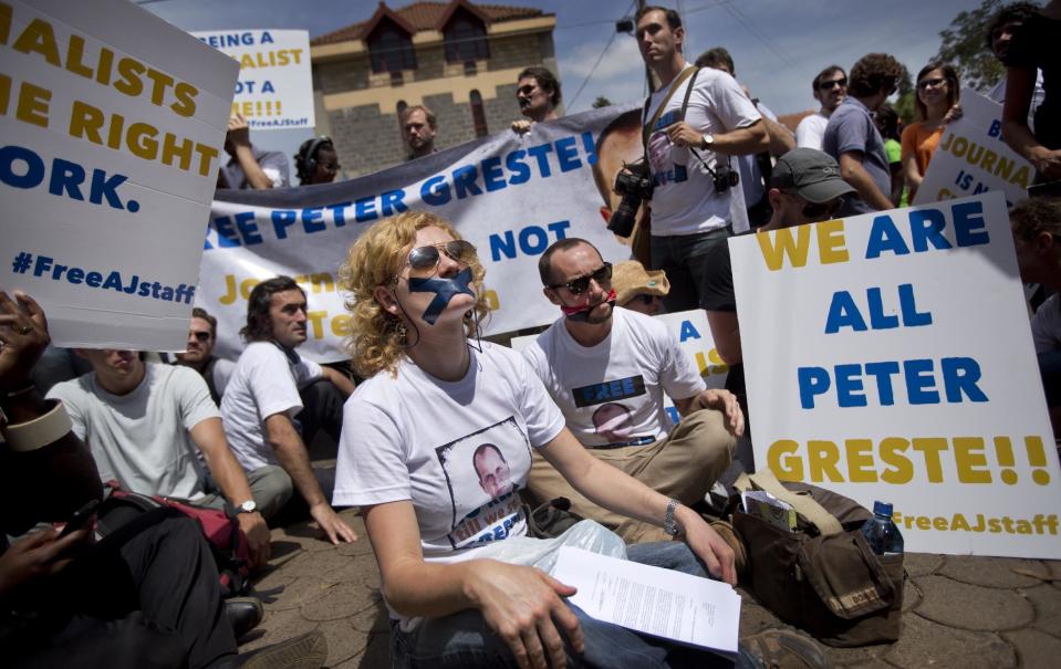 Members of the media sit with their mouths bound by tape and cloth in the colours of the Egyptian flag, signifying the silencing of the media, at a demonstration by Kenyan and Nairobi-based foreign media calling for the release of detained Al-Jazeera journalist Peter Greste and his colleagues, outside the Egyptian embassy in Nairobi, Kenya Tuesday, Feb. 4, 2014. Nairobi-based correspondent Greste was taken into custody in Egypt on Dec. 29 and is among 20 journalists working for Al-Jazeera, including four foreigners, who will face trial there on charges of joining or aiding a terrorist group and endangering national security - an escalation that raised fears of a crackdown on freedom of the press. (AP Photo/Ben Curtis)