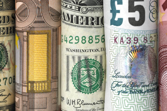 Dollar, euro and pound banknotes photographed on a gradient background. The banknotes are placed in a row and photographed macro