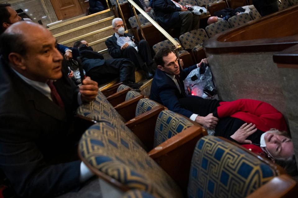 Rep. Jason Crow, D-Colo., comforts Rep. Susan Wild, D-Pa., while taking cover as protesters disrupt the joint session of Congress to certify the Electoral College vote (Tom Williams, AP)