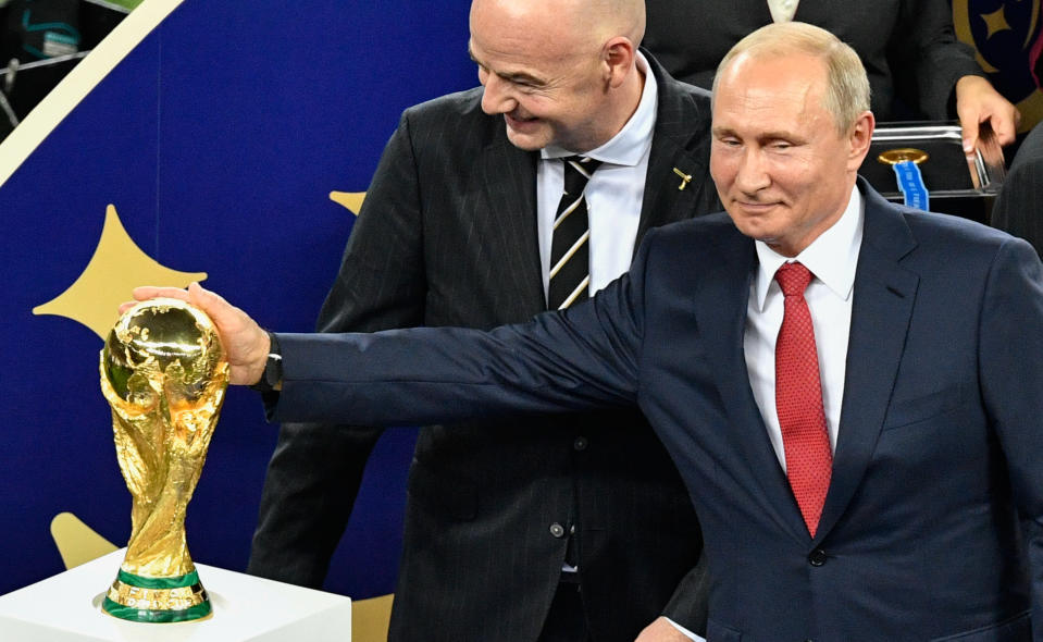 Vladimir Putin admires the World Cup trophy as FIFA president Gianni Infantino looks on. (Alexander Nemenov/AFP via Getty Images) 