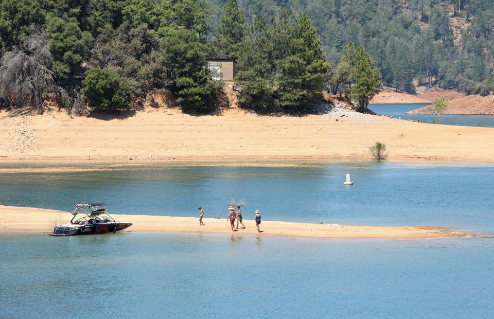 Visitors at Bridge Bay Resort return to their boat on Friday, July 12, 2024, as extreme hot temperatures cause the water in Lake Shasta to evaporate, leaving a familiar brown ring of shoreline.