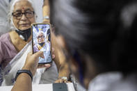 An Indian health worker takes photograph of an elderly woman while registering names before administering COVISHIELD vaccine at the Guwahati Medical College hospital in Gauhati, India, Monday, March 1, 2021. India is expanding its COVID-19 vaccination drive beyond health care and front-line workers, offering the shots to older people and those with medical conditions that put them at risk. (AP Photo/Anupam Nath)