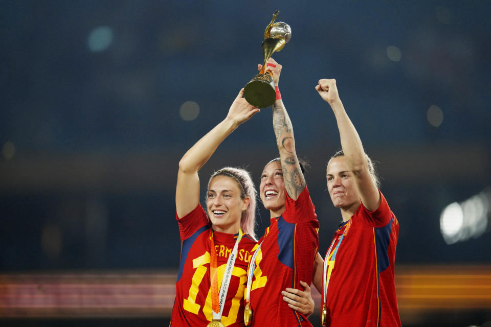FILE - Spain's Alexia Putellas, Jennifer Hermoso and Irene Paredes, from left, celebrate with the trophy at the end of the Women's World Cup soccer final between Spain and England at Stadium Australia in Sydney, Australia, Aug. 20, 2023. Spain faces reckoning over sexism in soccer after federation head Luis Rubiales kissed Hermoso during the Women’s World Cup medal ceremony. (AP Photo/Abbie Parr, File)