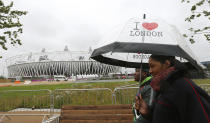 Pedestrians walk past the Olympic Stadium at the Olympic Park in Stratford, the location of the London 2012 Olympic Games, in east London July 16, 2012. REUTERS/Suzanne Plunkett (BRITAIN - Tags: SPORT OLYMPICS ENVIRONMENT)