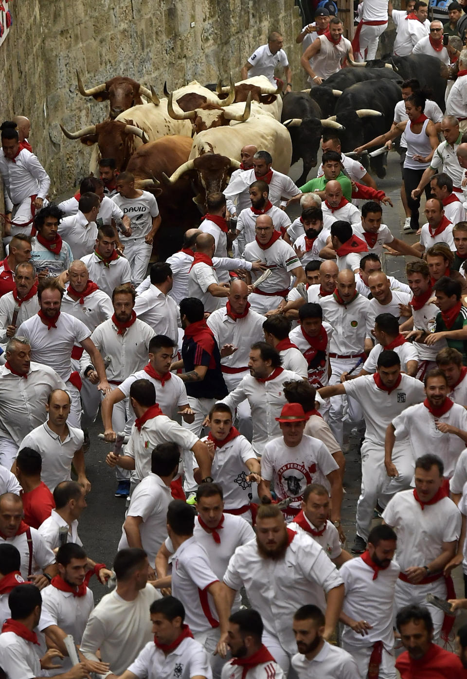 Revellers run next to fighting bulls during the running of the bulls at the San Fermin Festival, in Pamplona, northern Spain, Sunday, July 7, 2019. Revellers from around the world flock to Pamplona every year to take part in the eight days of the running of the bulls. (AP Photo/Alvaro Barrientos)