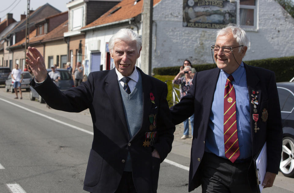 British RAF veteran George Sutherland, 98, left, waves as he walks with his son Alex Sutherland, while taking part in a VE Day charity walk to raise funds for Talbot House in Poperinge, Belgium, Friday, May 8, 2020. Sutherland walked from the Lijssenthoek war cemetery to Talbot house to raise money for the club which is currently closed due to coronavirus lockdown regulations. The club, founded in 1915 was a place for British soldiers to rest during both the First and Second World Wars. (AP Photo/Virginia Mayo)